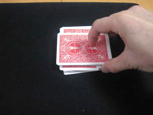 マジシャンは左側のトランプの束を横向きにして、右側のトランプの束の上に重ねる