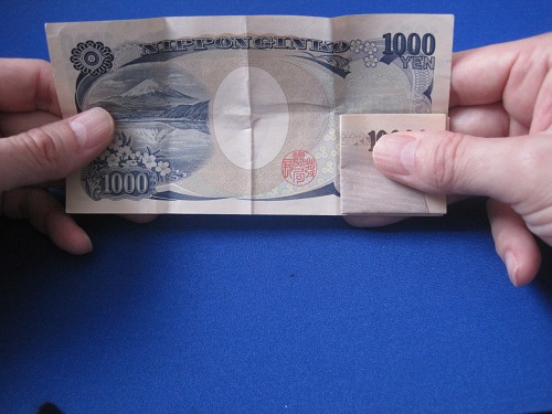一万円札が広がってこないように親指でぴったり押しつけます