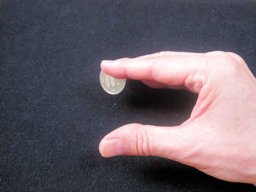 人差し指と中指でコインを持つ