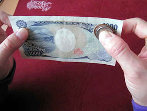 千円札の裏側に80円分のコインを隠し持つ