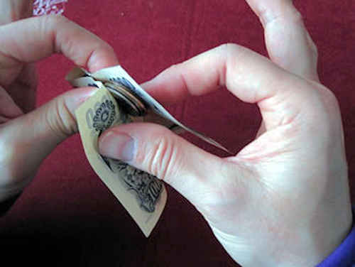 左手の人差し指と親指でコインをお札に挟んで持つ
