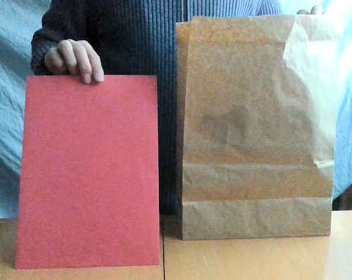 紙袋から赤色の筒抜け封筒を出します