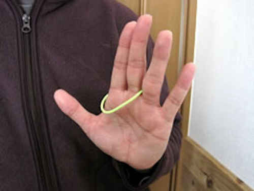 輪ゴムを４本の指ですくい上げるようにして左手を広げると、人さし指と中指に移動する