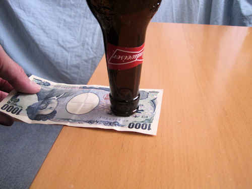 左手で千円札のはしをつまみます