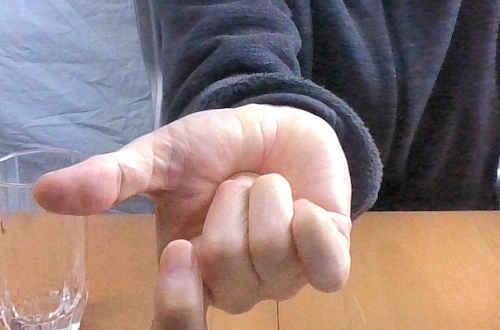 右手の中指と薬指を内側に曲げて親指の付け根にコインを当てる