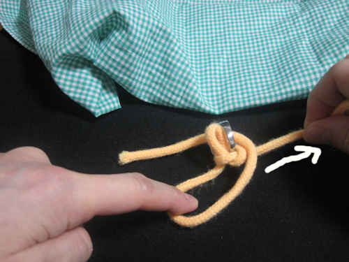 右手で紐を引っ張っているときに、左手の人差し指で紐を押さえています