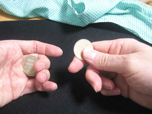 人差し指と親指でコインを持ちます
