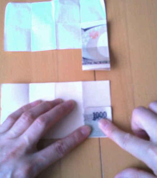 千円札を折り目に沿って八つ折りにする。