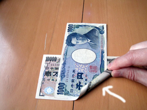 一万円札の上に千円札を重ねて丸めていきます。