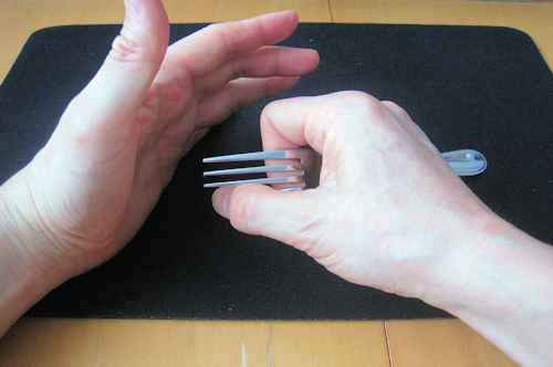 左手でフォークの先を隠したときに、右手の親指でフォークの先端１本を曲げる