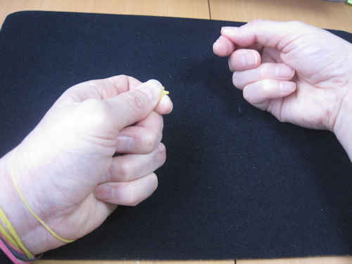 右手の輪ゴムを離して、左手の人差し指と親指で輪ゴムを持つ
