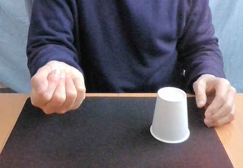 右手は握ったままで、紙コップはテーブルに置きます