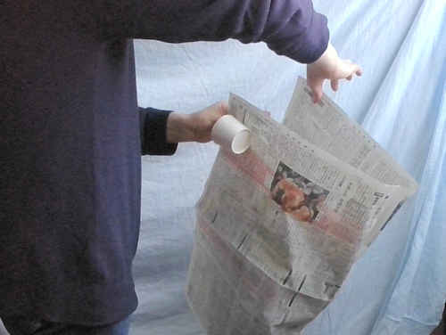 右手で持っている新聞紙を左手にもっていきます