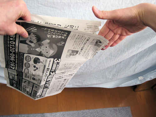 新聞紙の折り目から、右手で破ります。